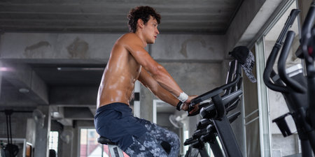 Caucasian topless athletic man cardio riding on bicycle at gym fitness. muscular people workout on cycling machine station exercise training. healthy and lifestyle concept.の写真素材