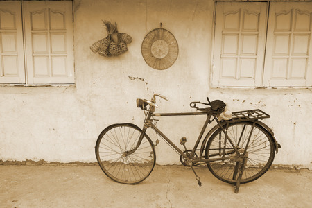 Old rusty vintage bicycle near the concrete wallの写真素材