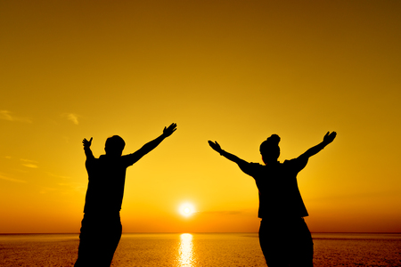 Silhouette of a female and male on the beautiful sunset at the sea, Freedom concept.の写真素材