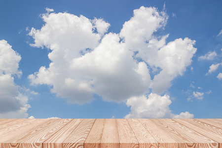 Wood table top on blue sky with clouds background - can be used for display or montage your productsの写真素材
