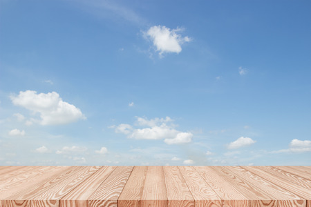 Wood table top on blue sky with clouds background - can be used for display or montage your productsの写真素材