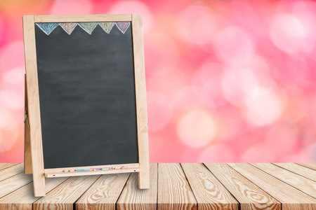 Wood table top on blur pink background of flower with blank blackboard - can be used for display or montage your productsの写真素材