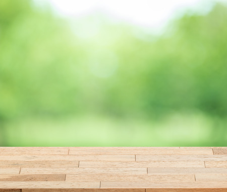 Wood table top on blur green background of trees in the park - can be used for display or montage your products.の写真素材