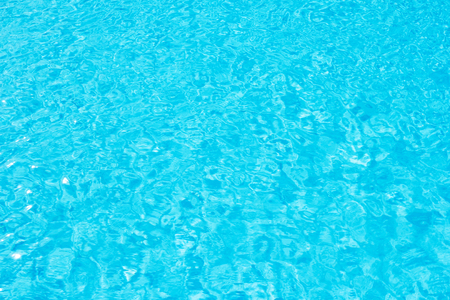 Swimming pool blue water surface with bright sun light reflection.の写真素材