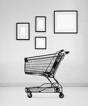 shopping cart with empty frames in white roomの写真素材