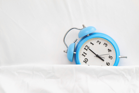 alarm clock on bed sheetsの写真素材
