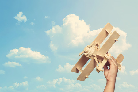 toy airplane in hand of kid and sky background (retro filter)の写真素材