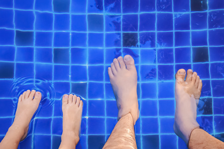 foot of father and son relaxing on the poolの写真素材
