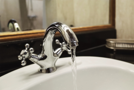 faucet and water flow in the bathroomの写真素材