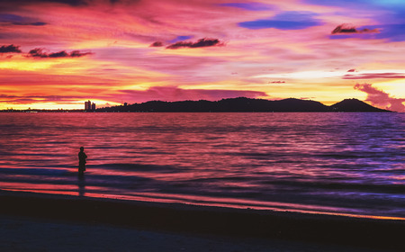 silhouette of a man and sea coast at sunsetの写真素材