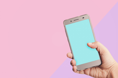 hand holding phone with blue screen isolated on pink and purple backgroundの写真素材