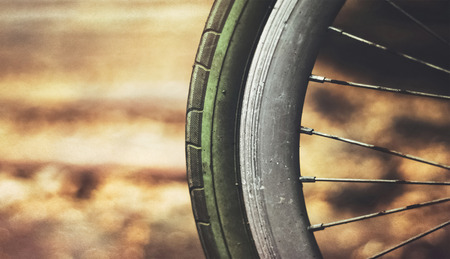 old rusty bicycle wheel against warm blur background (retro effect)の写真素材