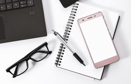 top view office desk (smartphone laptop pen notebook and glasses on white background)の写真素材