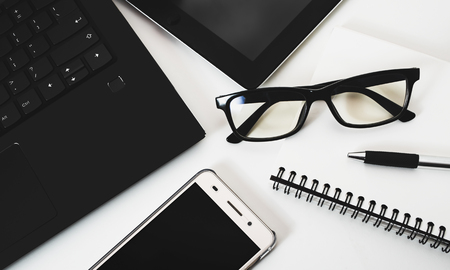 top view office desk (smartphone laptop pen notebook tablet and glasses on white background)の写真素材