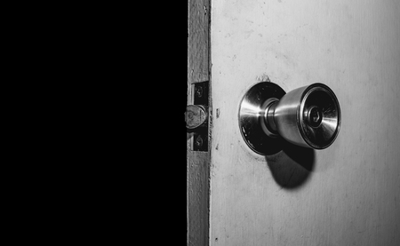 old white wooden door opening in the darkの写真素材