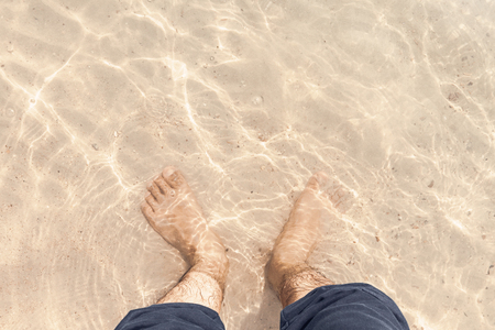 barefoot in clear water on the beachの写真素材
