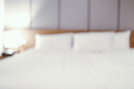 blurred white bed in bedroom interior backgroundの写真素材