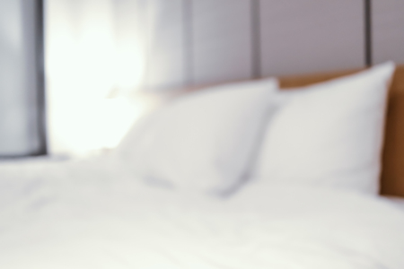 blurred white bed in bedroom interior backgroundの写真素材