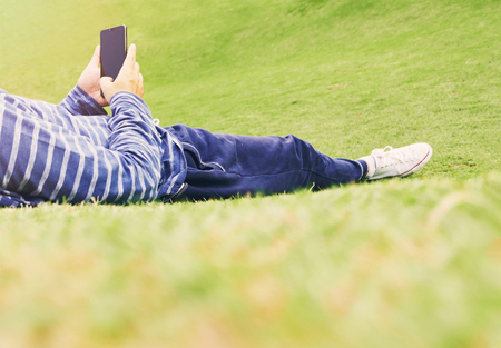 a man lying down and use smartphone on yardの写真素材
