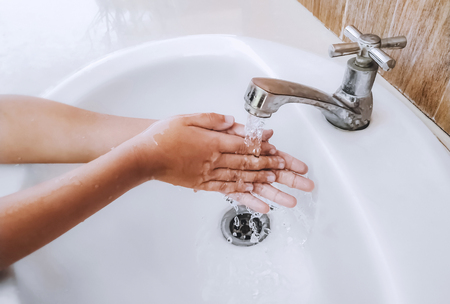 kid washing hand on white basinの写真素材