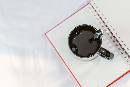 a coffee cup and a notebook on white bedの写真素材