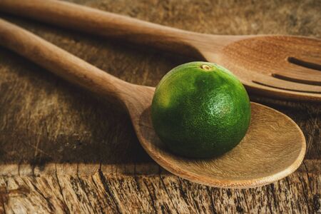 lime with wooden spoon on cutting boardの写真素材