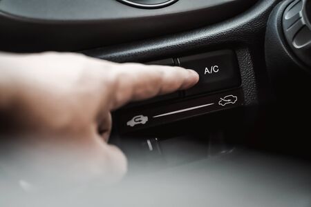 hand pressing on air conditioning button inside the carの写真素材