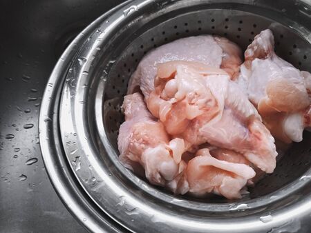 washing fresh raw chicken wingstick on kitchen sinkの写真素材