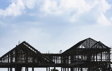 building house structure with scaffold in construction site against blue sky backgroundの写真素材