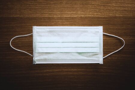 a medical mask on a wooden background. advice for the public to wear face masks to protect the respiratory system from coronavirus disease (COVID-19).の写真素材