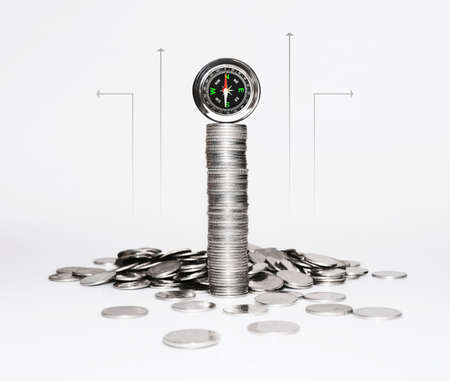 the financial direction of the economy and investment. silver coin and compass on white. business growth and money supply concept.の写真素材