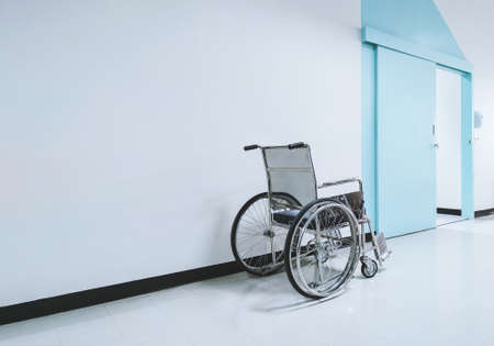 a wheelchair is waiting for a patient in front of an examination room in the hospital. background...
