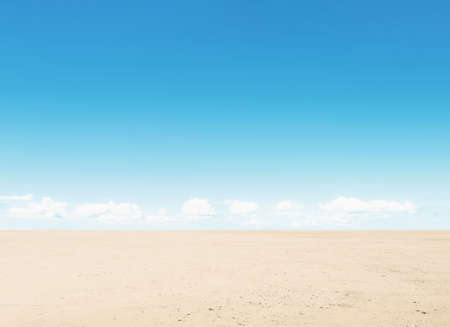 Arid desert with the blue sky background. On the dirt road that is wide and empty. The horizon and flat land.の写真素材