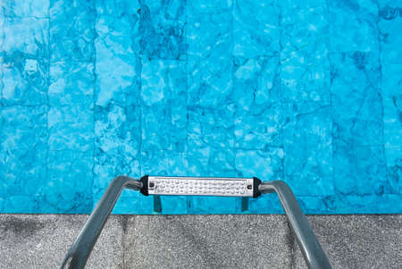 Ladder on the poolside top view. Sunshine through the clear water of the swimming pool. Relaxation in the summertime. Hotel and resort accommodation.の写真素材