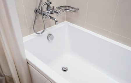 Hot and cold water taps for bathing and relaxing in the bathroom.  Luxury white bathtub. Hotel and...