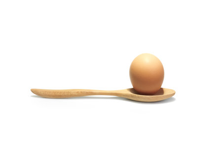 Chicken egg with a wooden spoon on white background. Prepare to cooking.の写真素材