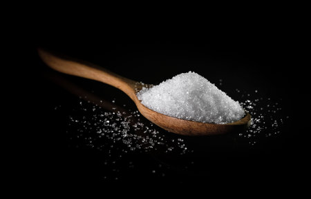 White sugar with wooden spoon on dark table background. Sweet seasoning.の写真素材