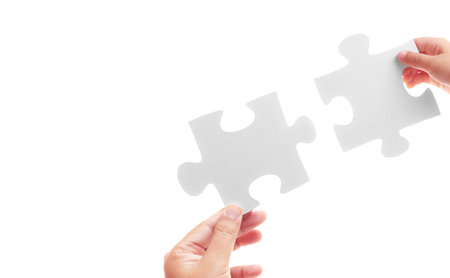 Jigsaw puzzles in the hands of child and adult on a white background. Different ages but support each other. Relationships within the family. Respect adults and be kind to children concept.の写真素材