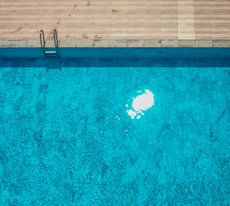 Top view of swimming pool.  Ladder on the poolside. Tropical sunshine and clear water. Relaxation in the summertime. Hotel and resort accommodation.の写真素材