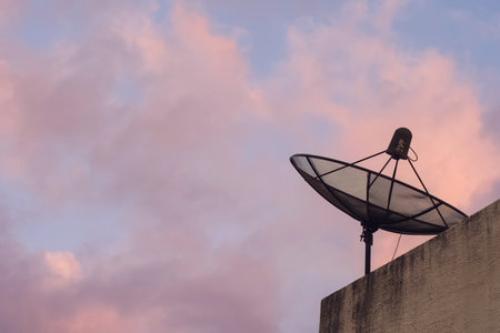 Satellite dish on the rooftop of building against evening sky background.の写真素材