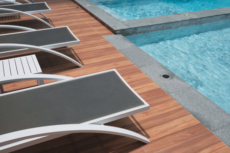 Swimming pool with sun loungers and deck chairs in a hotel. Relaxation on sunny day.の写真素材