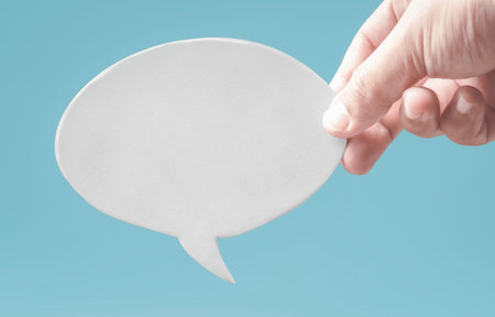 Hand holding paper tag. Blank speech bubble. Feedback comment. Business suggestion.の写真素材