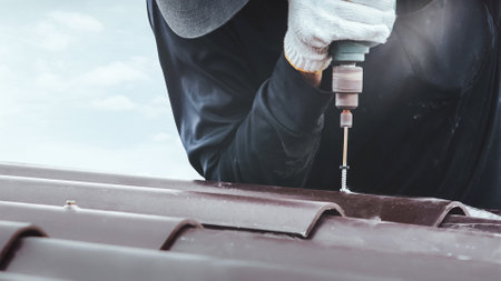 A builder working on the roof. House maintenance. Repair and replacing cement roof tiles.の写真素材