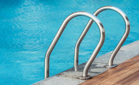 Chrome handrails of the pool. Hotel spa and resort accommodation. Ladder on the poolside. Relaxation in the summertime.の写真素材