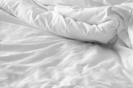 Wrinkled white bedsheet background. Cozy fabric texture surface. Untidy duvet backdrop. Relaxation and comfortable accommodation.の写真素材