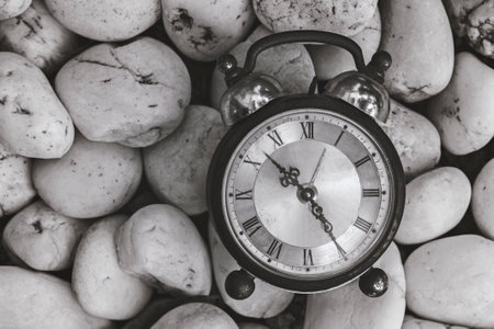 Antique alarm clock on pebbles. The concept of the passage of time. Vintage object and nature background.の写真素材
