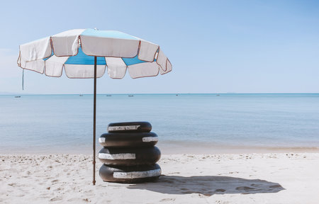 Umbrella and rubber rings on the white sand. Tropical beach background. Travel and tourism. Vacation on sunny day. Pattaya beach seascape in thailand.の写真素材