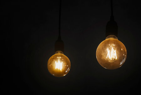 Light bulb hanging in a dark room. Household electricity consumption. Ideas and problem solving.の写真素材