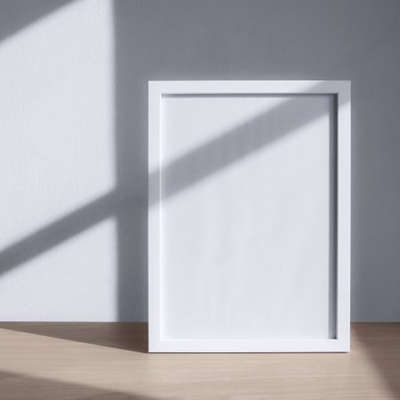Sunlight shadows from the window on the blank frame. Frame mockup on the desk.の写真素材