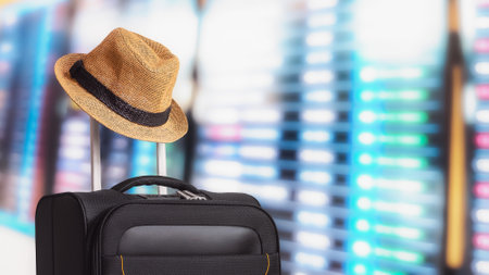 Hat and suitcase against flight information board in airport. Business tourism. Transportation and travel.の写真素材